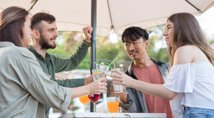 Przyjaciele wznoszą toast podczas urodzinowej imprezy, ciesząc się wspólnym czasem pod parasolem.