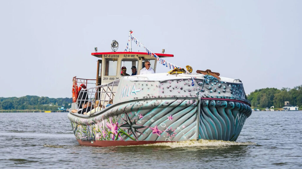 Statek Mila z malowanym kadłubem w motywy morskie, pełen pasażerów podczas rejsu po jeziorze Jamno.