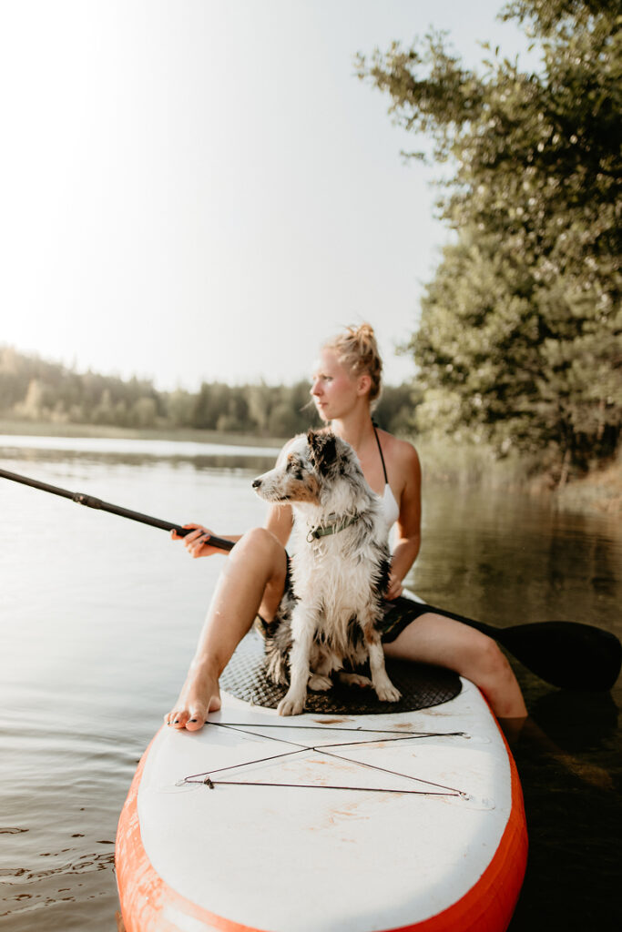 Kobieta z psem na desce SUP – aktywności wodne z czworonogiem nad jeziorem w Mielnie.